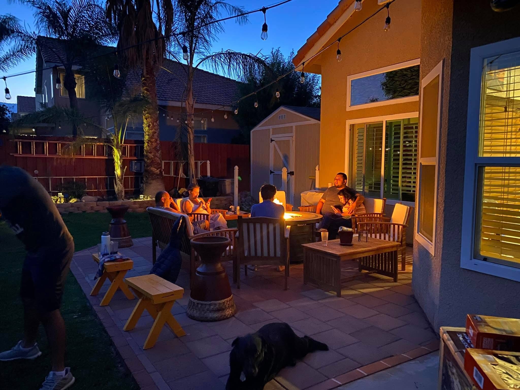 Family gathered around a fire pit in the finished backyard at night